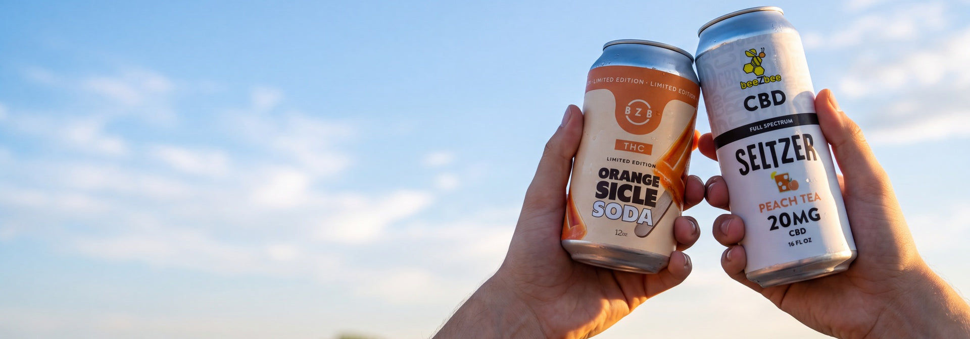 beeZbee BOGO 50% off beverages, Orangesicle THC soda and Peach Tea CBD seltzer held against a summer sky